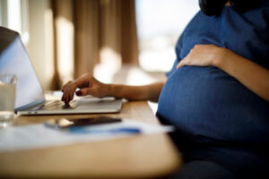 Pregnant woman using laptop at home