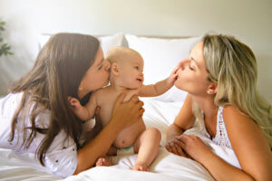 The Two lesbian mother and baby on bed having fun